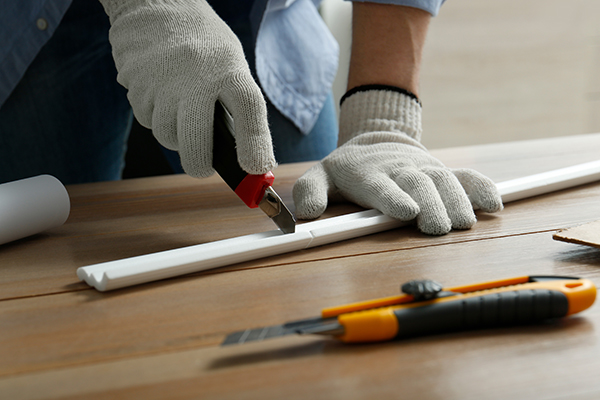 An image of a contractor cutting a piece of moulding for a project.