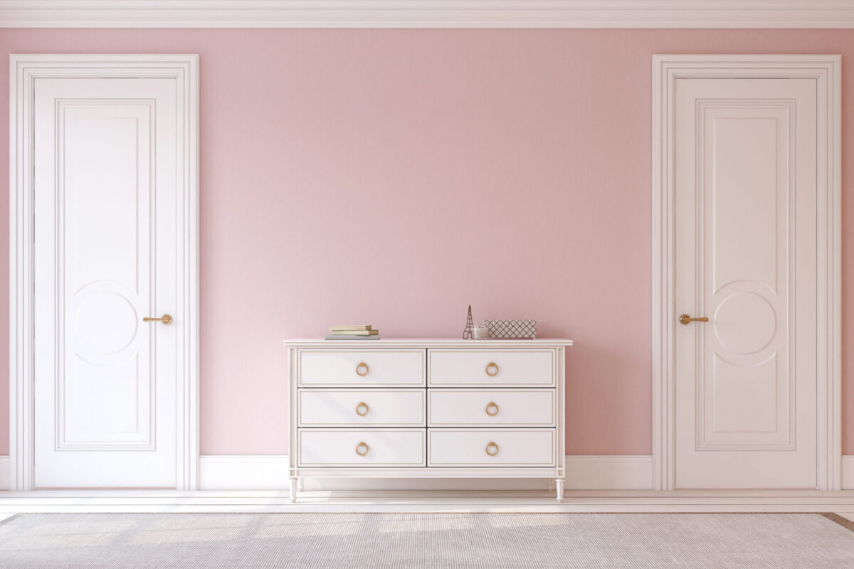 Two white doors with white door casings in a pink hallway, separated by a dresser.