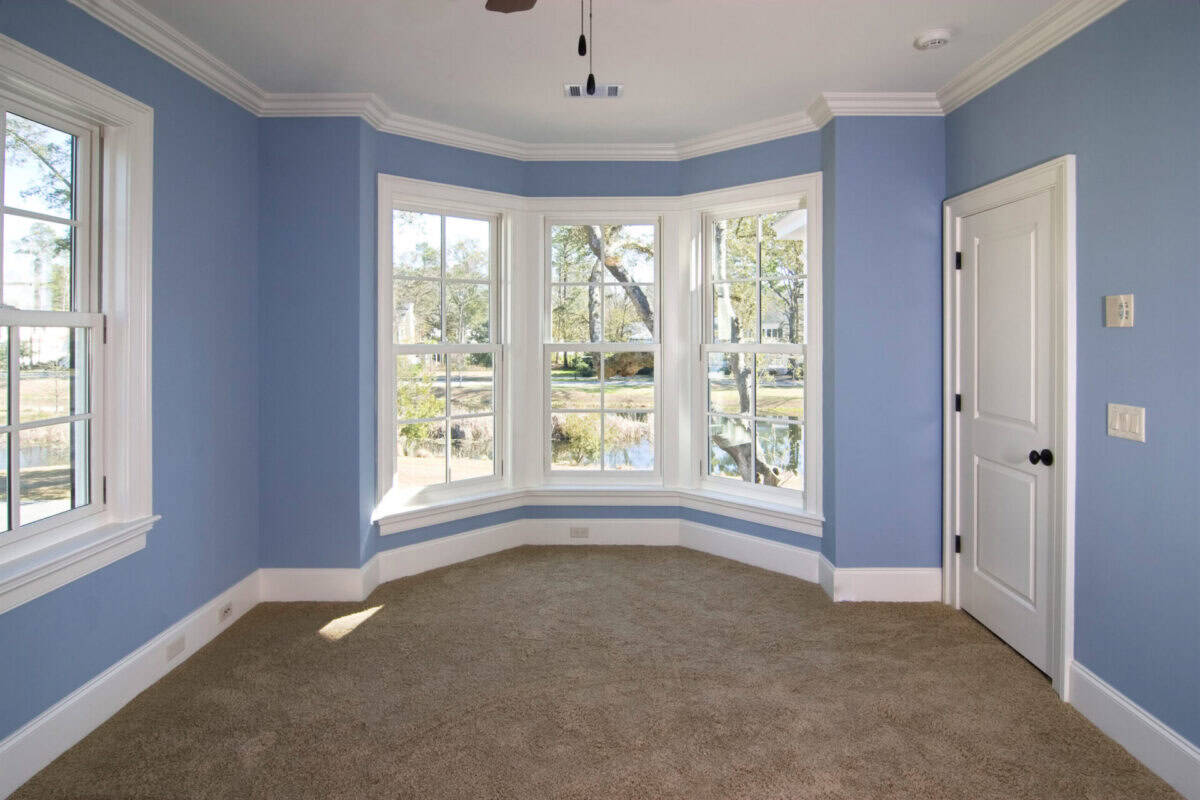 A blue room with white baseboard, window, and ceiling trim.