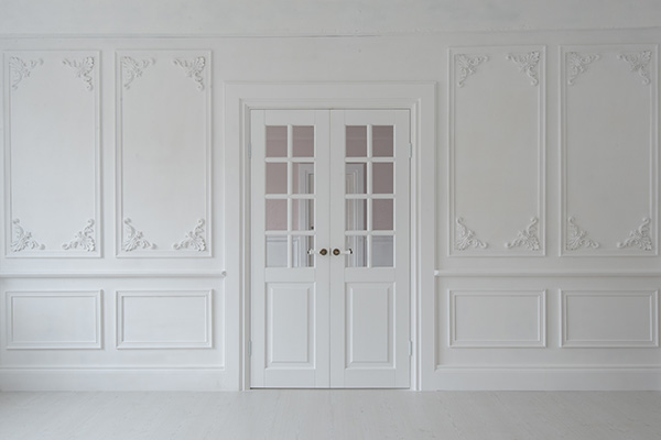 An image of elaborate moulding on the walls and around a door, all white