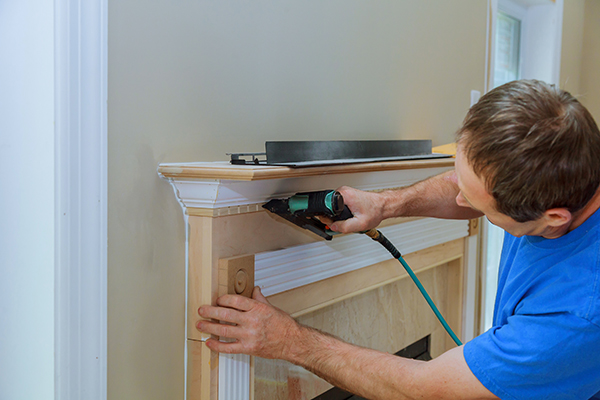 A contractor installs moulding above a fireplace.