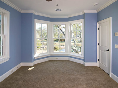 A blue room with white baseboard, window, and ceiling trim.