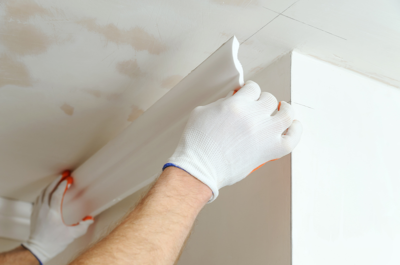 A photo of someone in white gloves installing white crown moulding