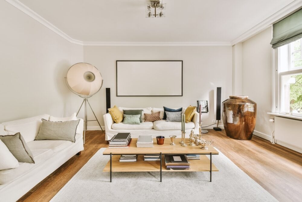 Elegant living room with white walls and wooden flooring, featuring decorative mouldings and stylish.