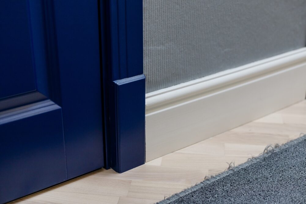 Cross-section view showing how a plinth block is thicker than both the casing above it and the baseboard beside it