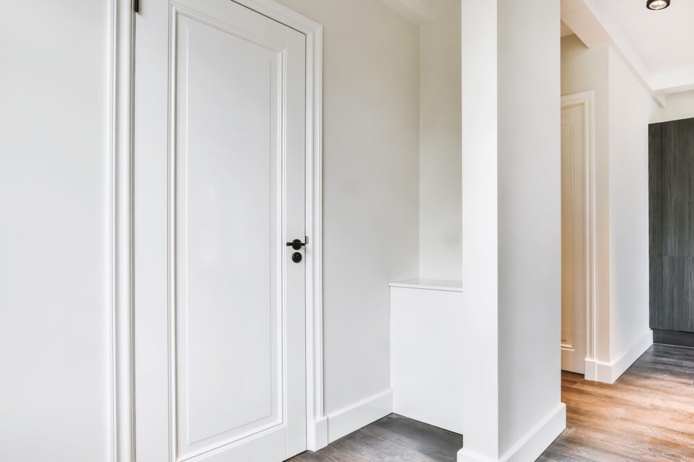 Plinth block installed at the base of a painted door casing where it meets a tall baseboard